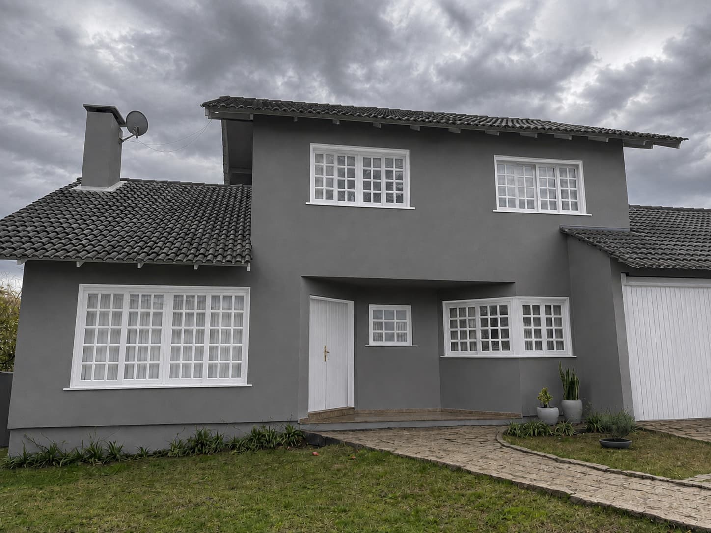 Sala de apartamento reformada com piso de concreto polido, paredes brancas e caixilhos metálicos pretos